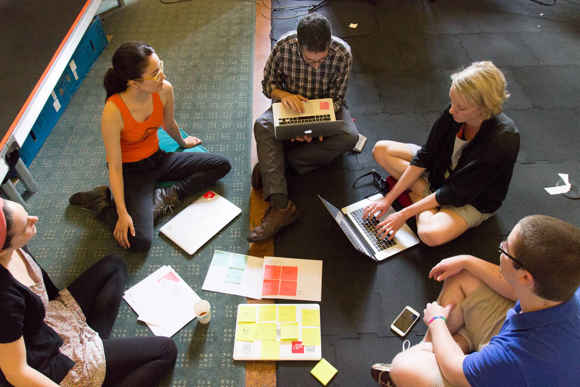 Five people in a circle with their laptops sharing their notes"