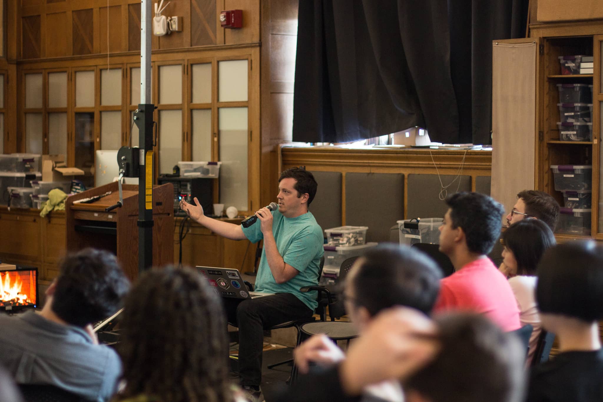 Man sitting in front of the classroom speaking energetically into a microphone"